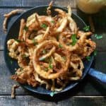 A cast iron pan full of fried onion rings.