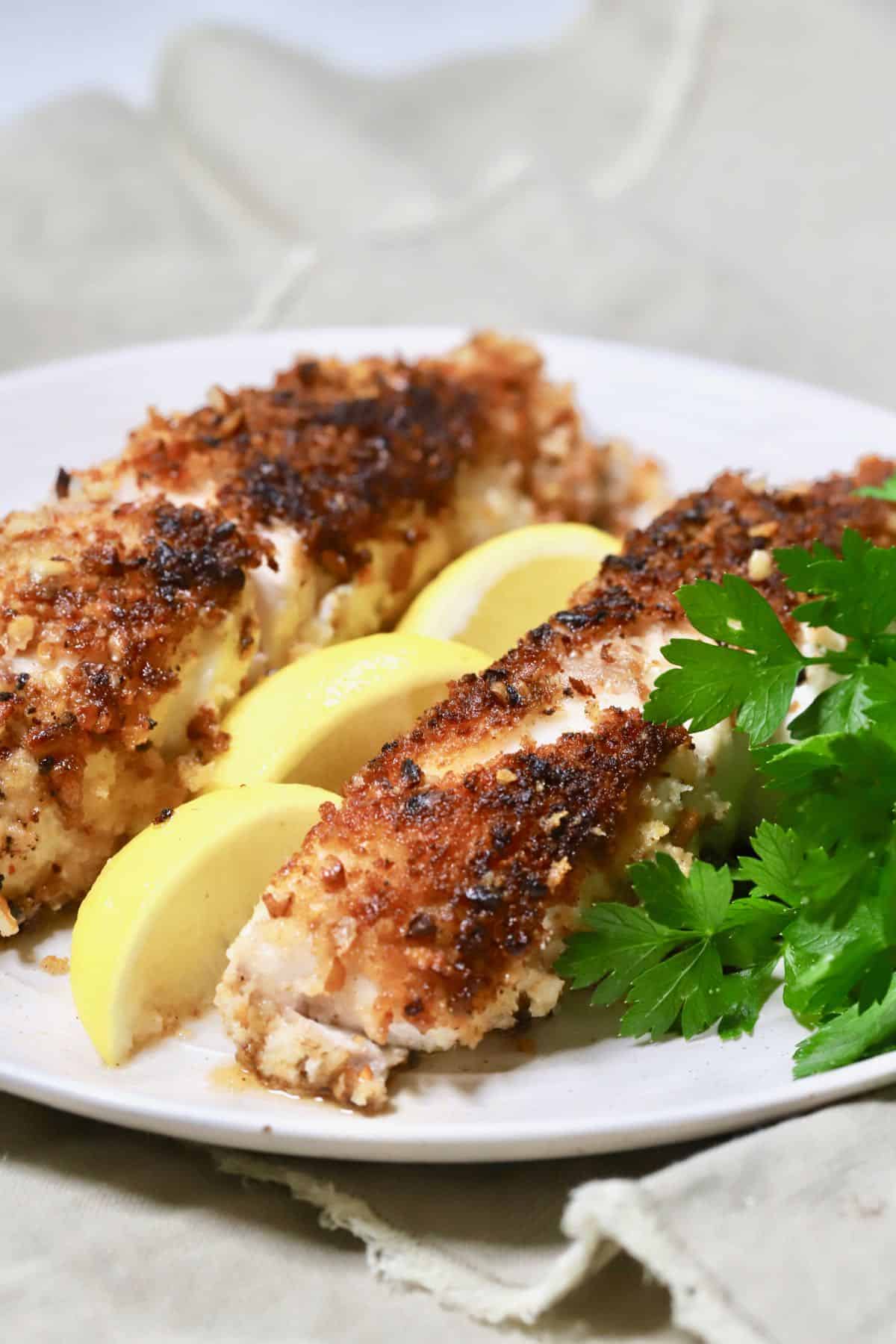 Two pecan crusted grouper fillets on a plate. 