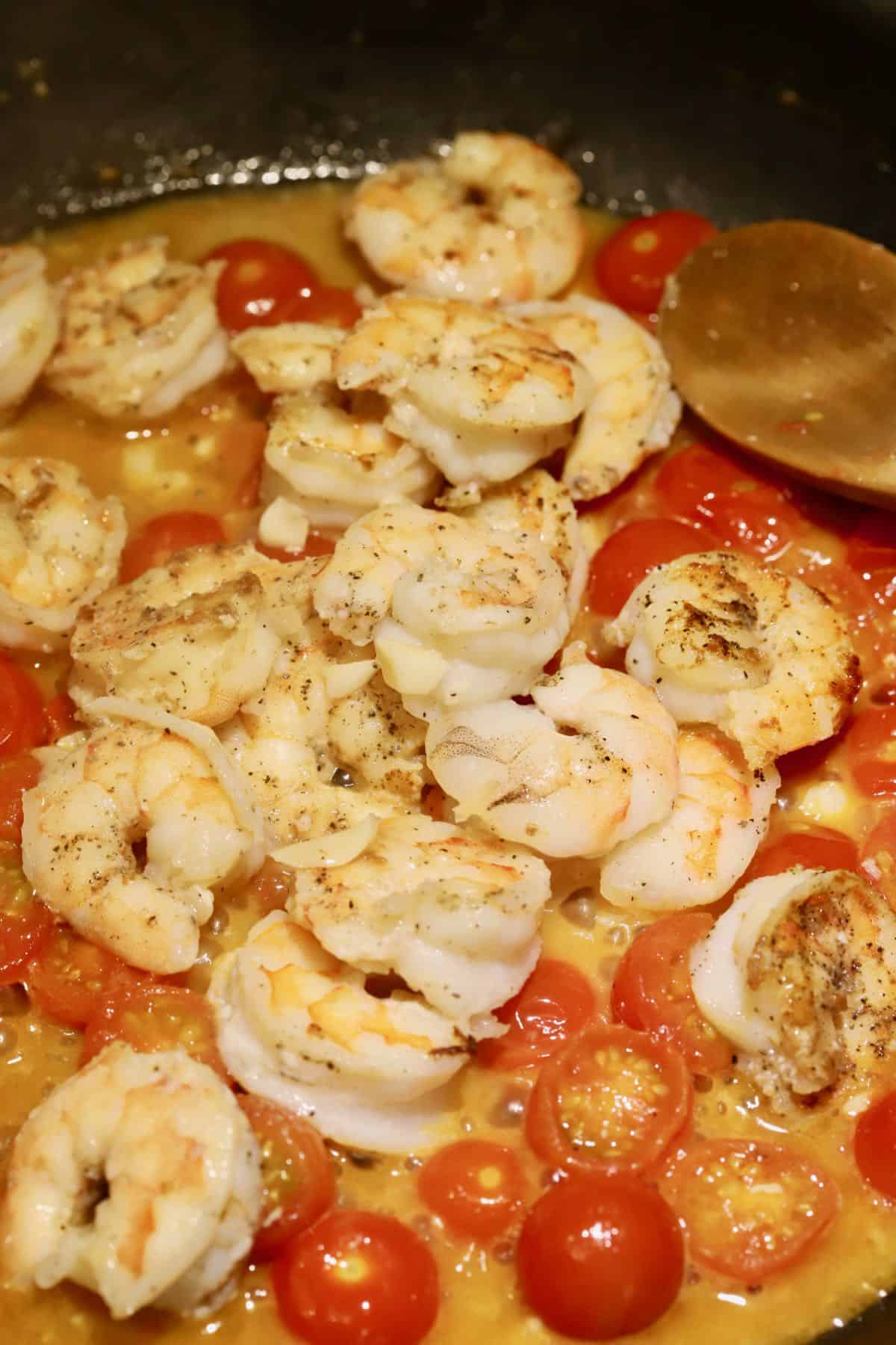 Shrimp and cherry tomatoes cooking in a skillet.