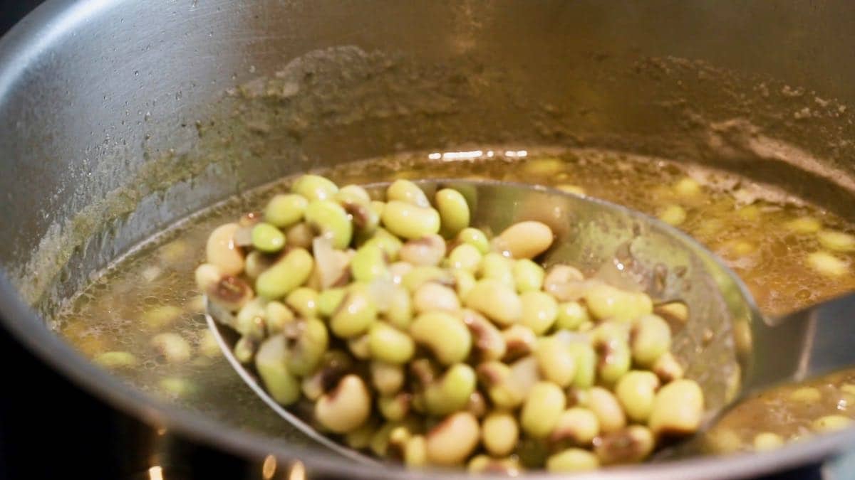 A large spoonful of peas in a saucepan.