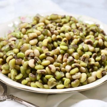 A white bowl full of cooked purple hull peans.