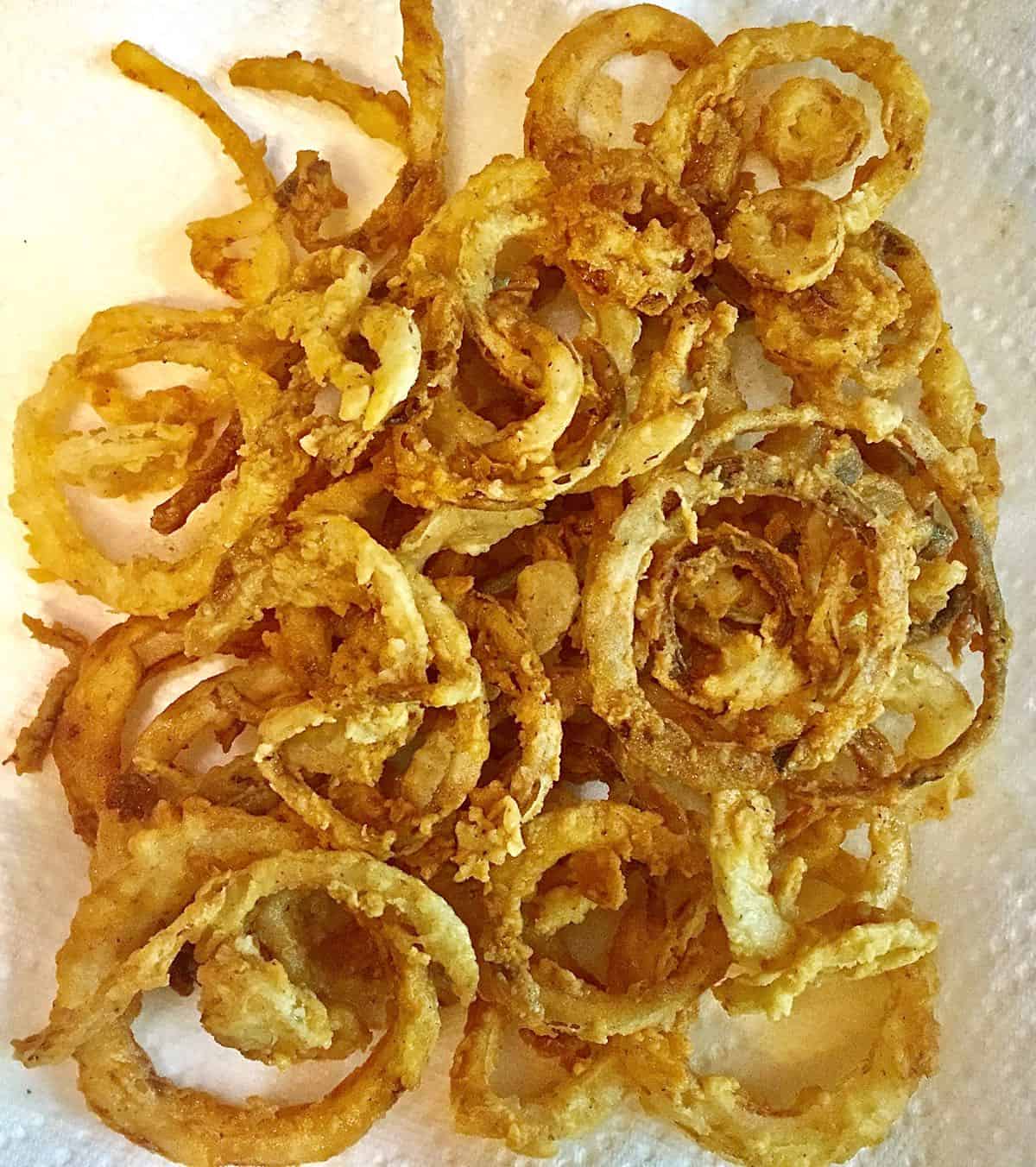 Fried onion rings draining on a paper towel.