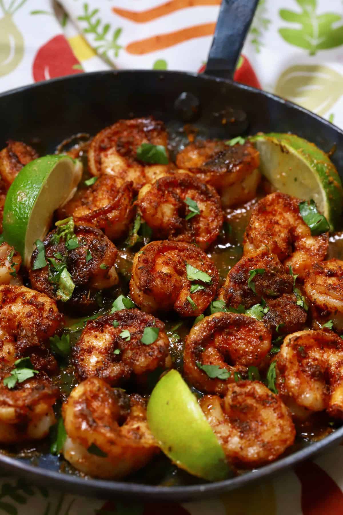 Lime slices, along with cooked shrimp in a skillet.