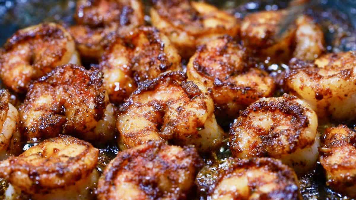 Blackened shrimp cooking in a skillet.