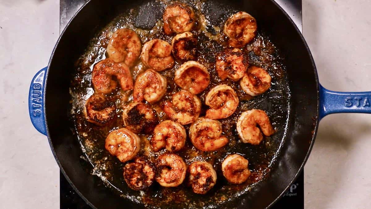 Blackened shrimp cooking in a cast iron skillet. 