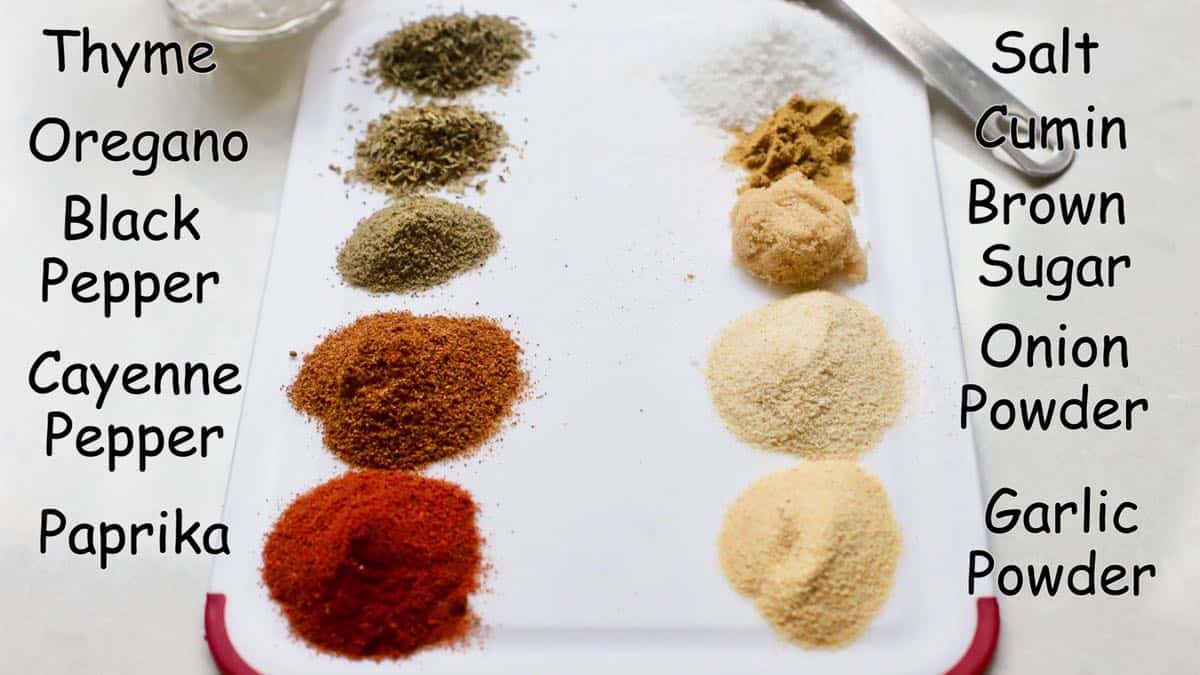 A cutting board with ten piles of various spices including oregano and thyme.