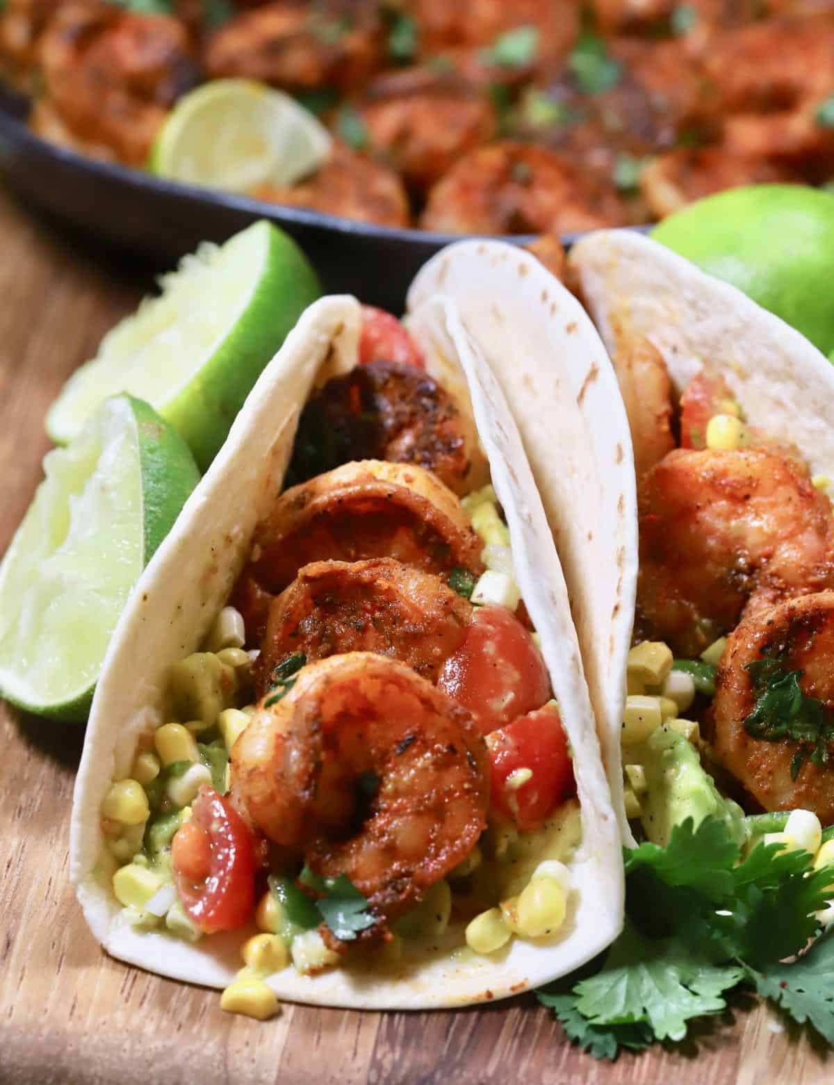 A shrimp taco with avocado salsa on a cutting board.