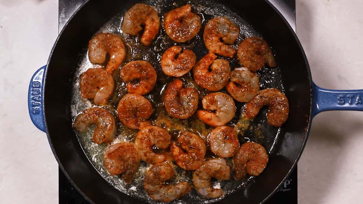 Blackened shrimp cooking in a skillet.