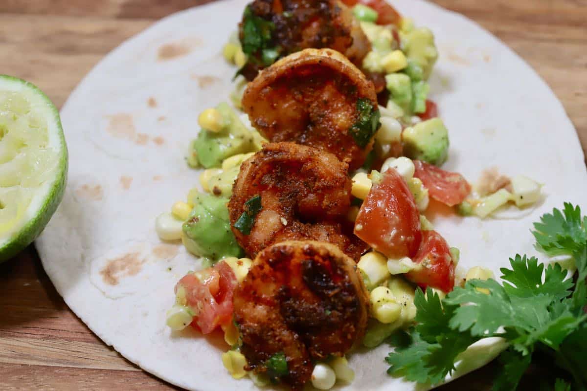 A flour tortilla topped with shrimp and avocado salsa.