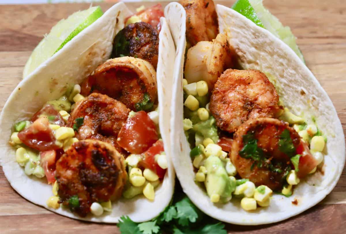 Two shrimp tacos with corn and avocado.