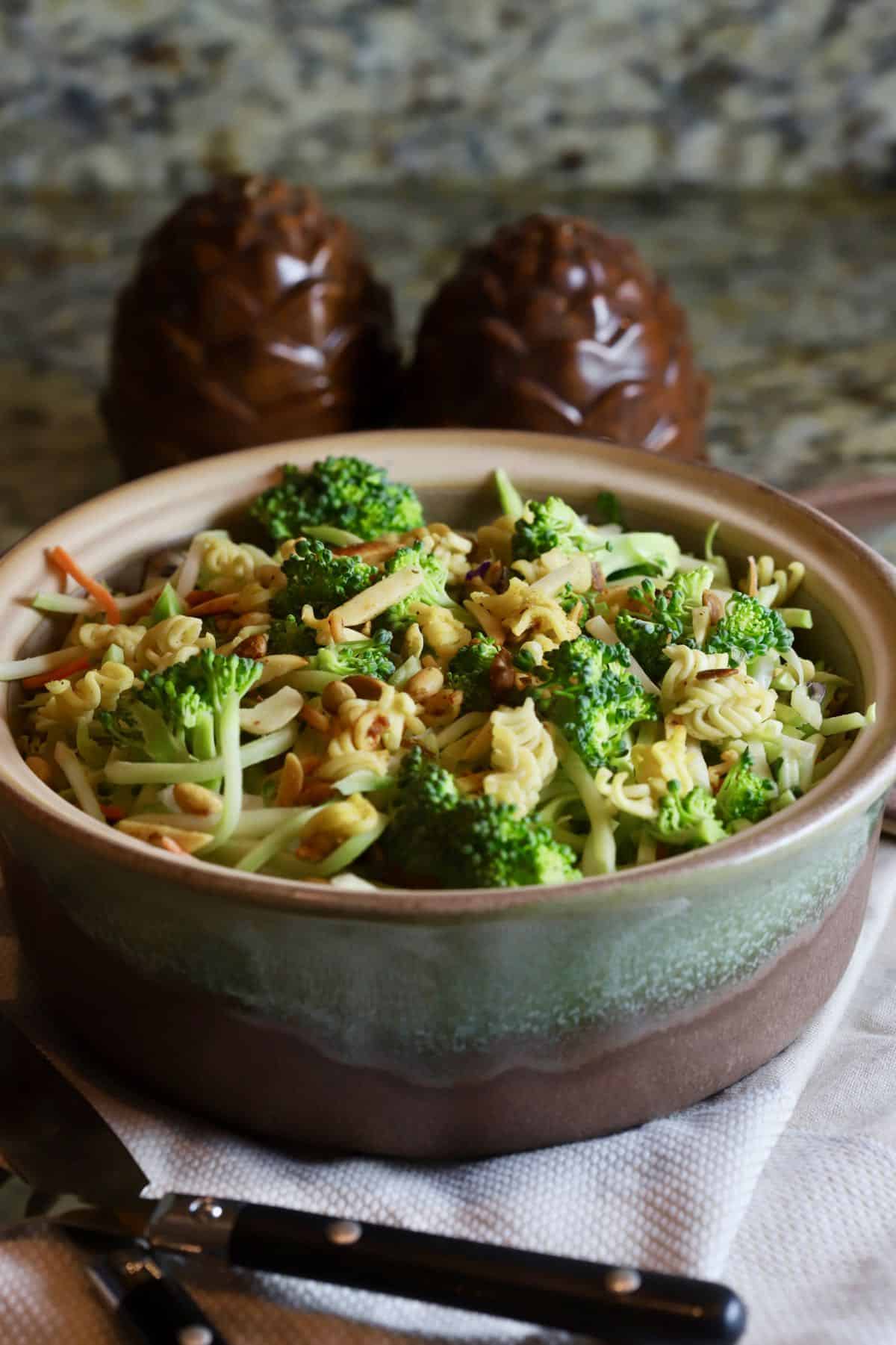 A pottery bowl full of broccoli slaw and ramen noodles. 