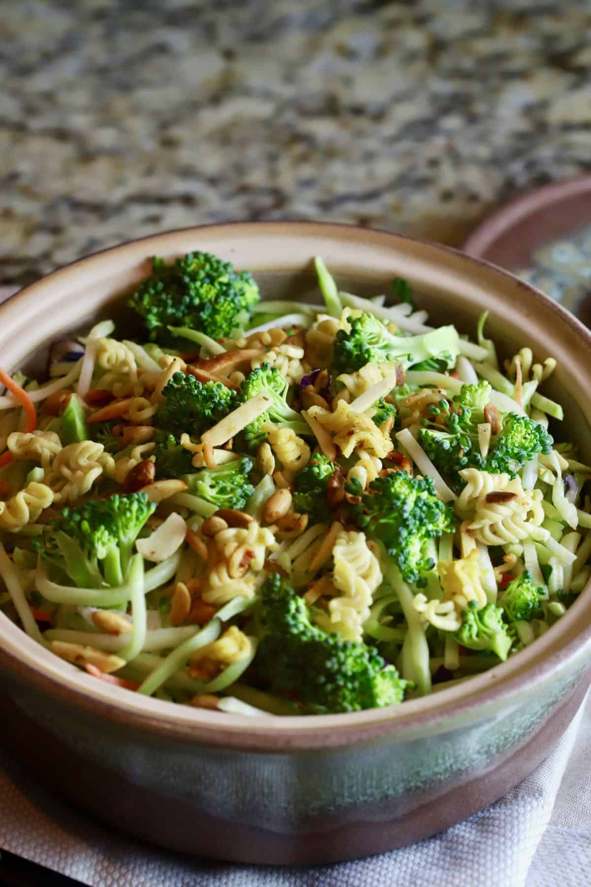 Broccoli florets, slaw and ramen noodles in a pottery bowl ready to serve. 