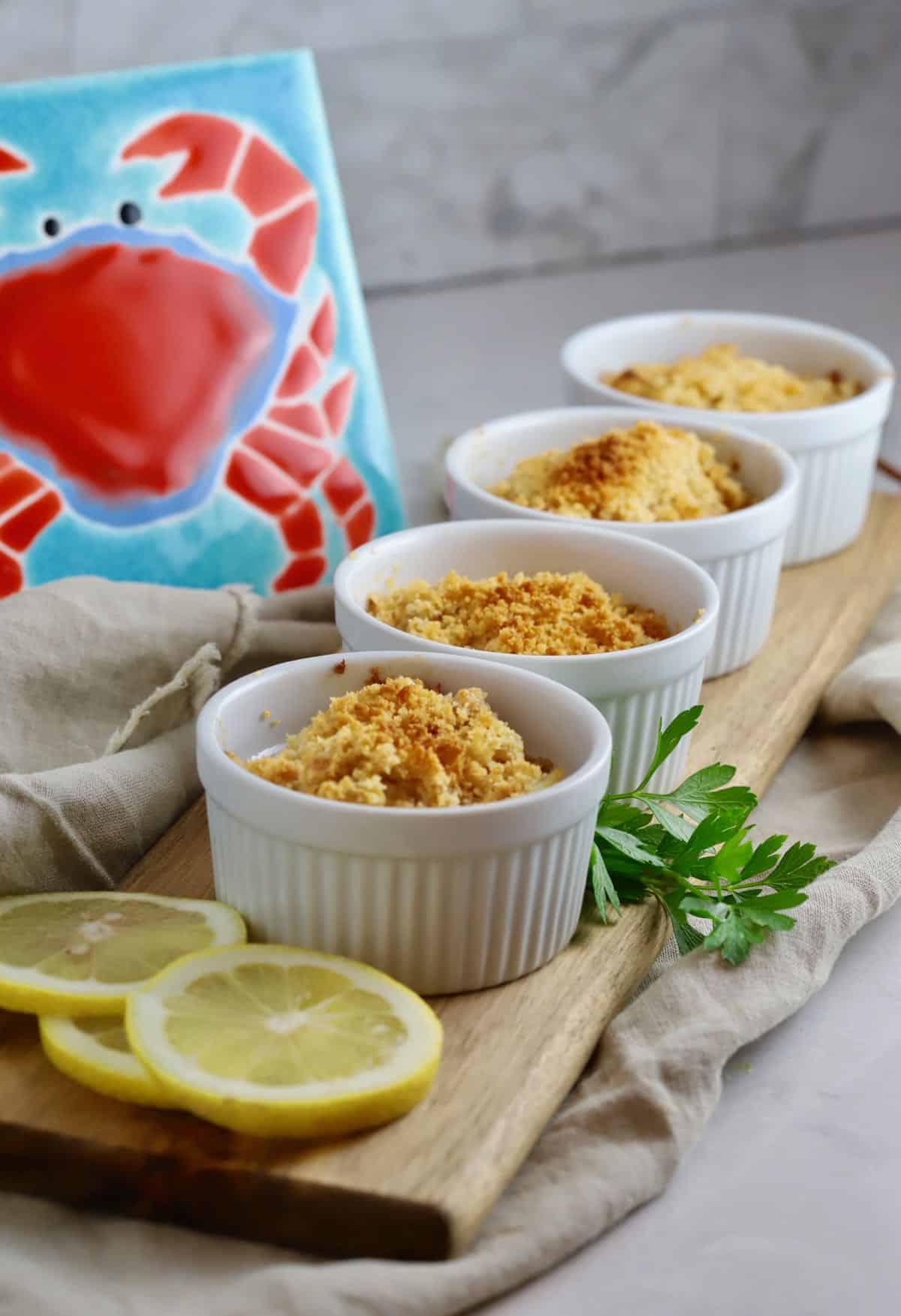 Deviled crab in four ramekins on a cutting board. 