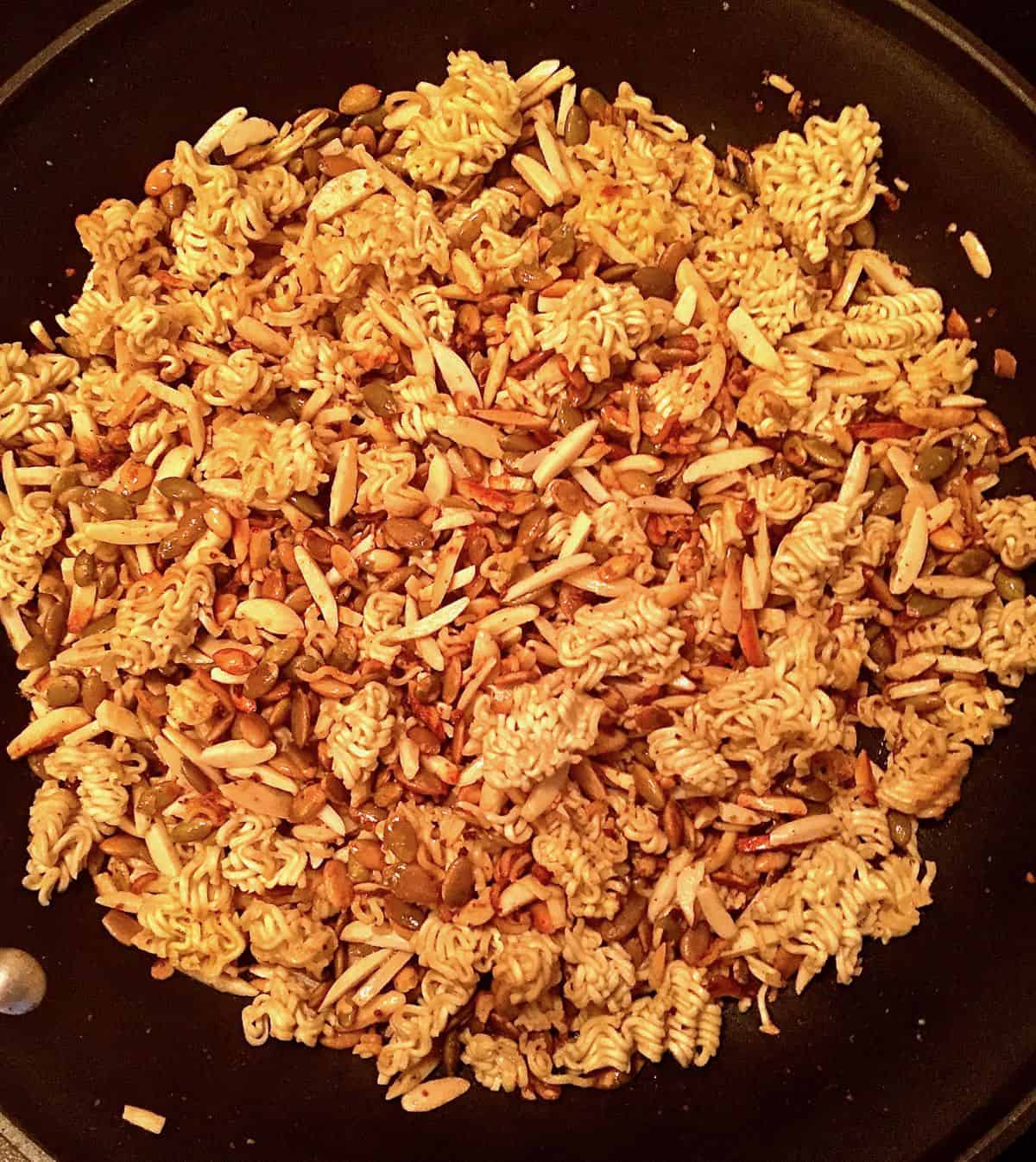 Crushed ramen noodles, slivered almonds and sunflower seeds in a skillet. 