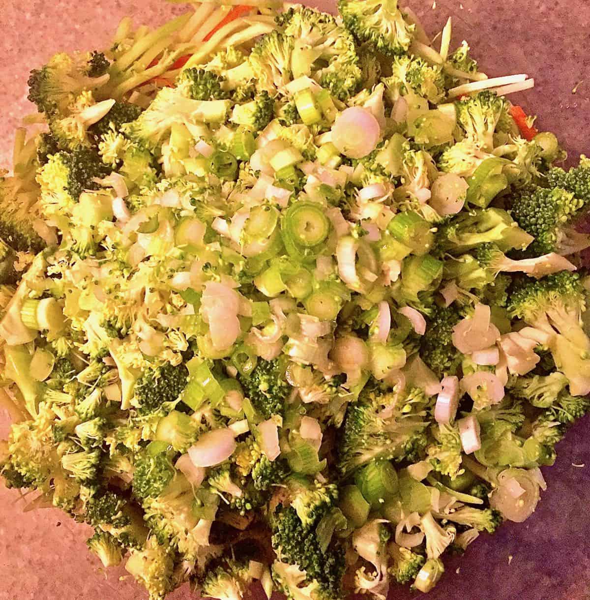 Chopped scallions, broccoli slaw and broccoli in a bowl. 