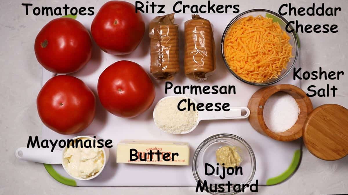 Fresh tomatoes, a roll of crackers, cheddar and parmesan cheeses, and a stick of butter.