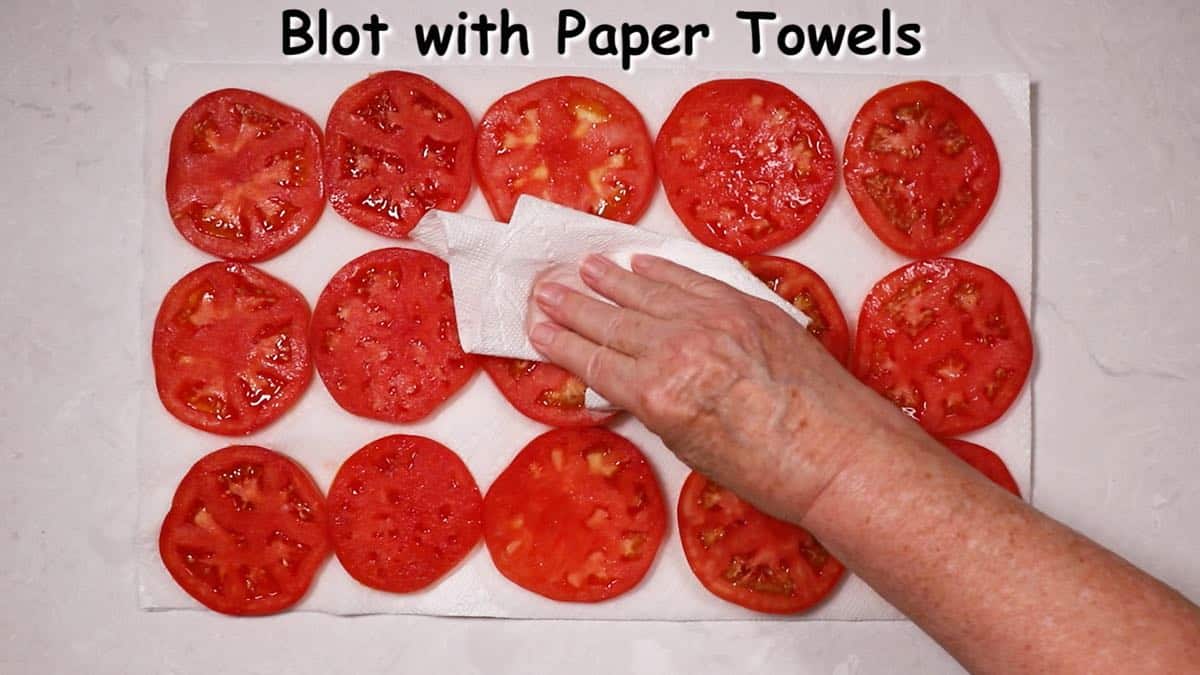 Sliced tomatoes on paper towels draining. 