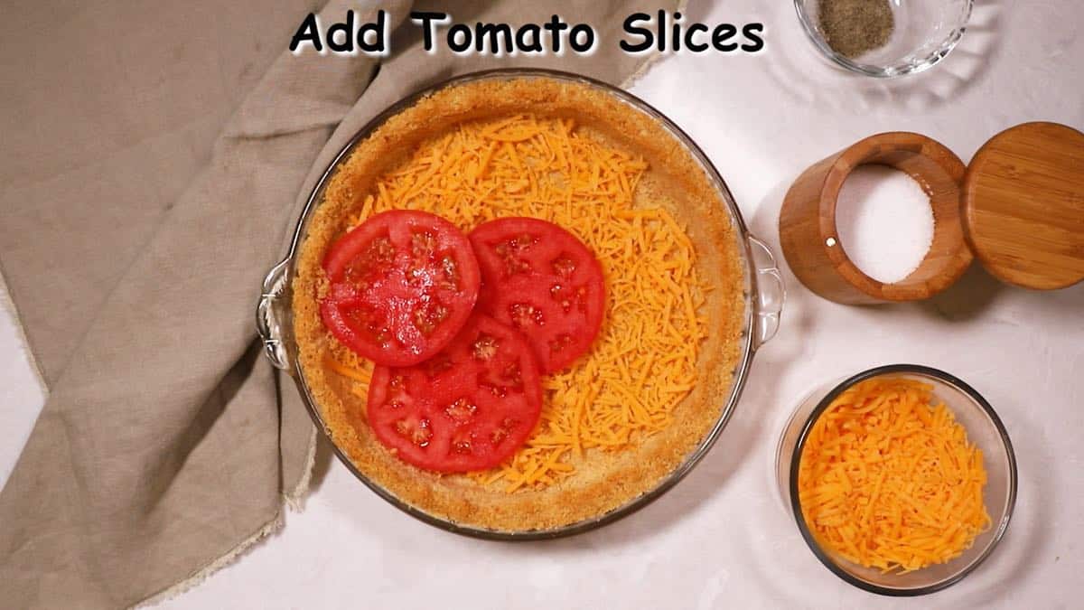 A pie crust topped with a layer of cheese and sliced tomatoes. 