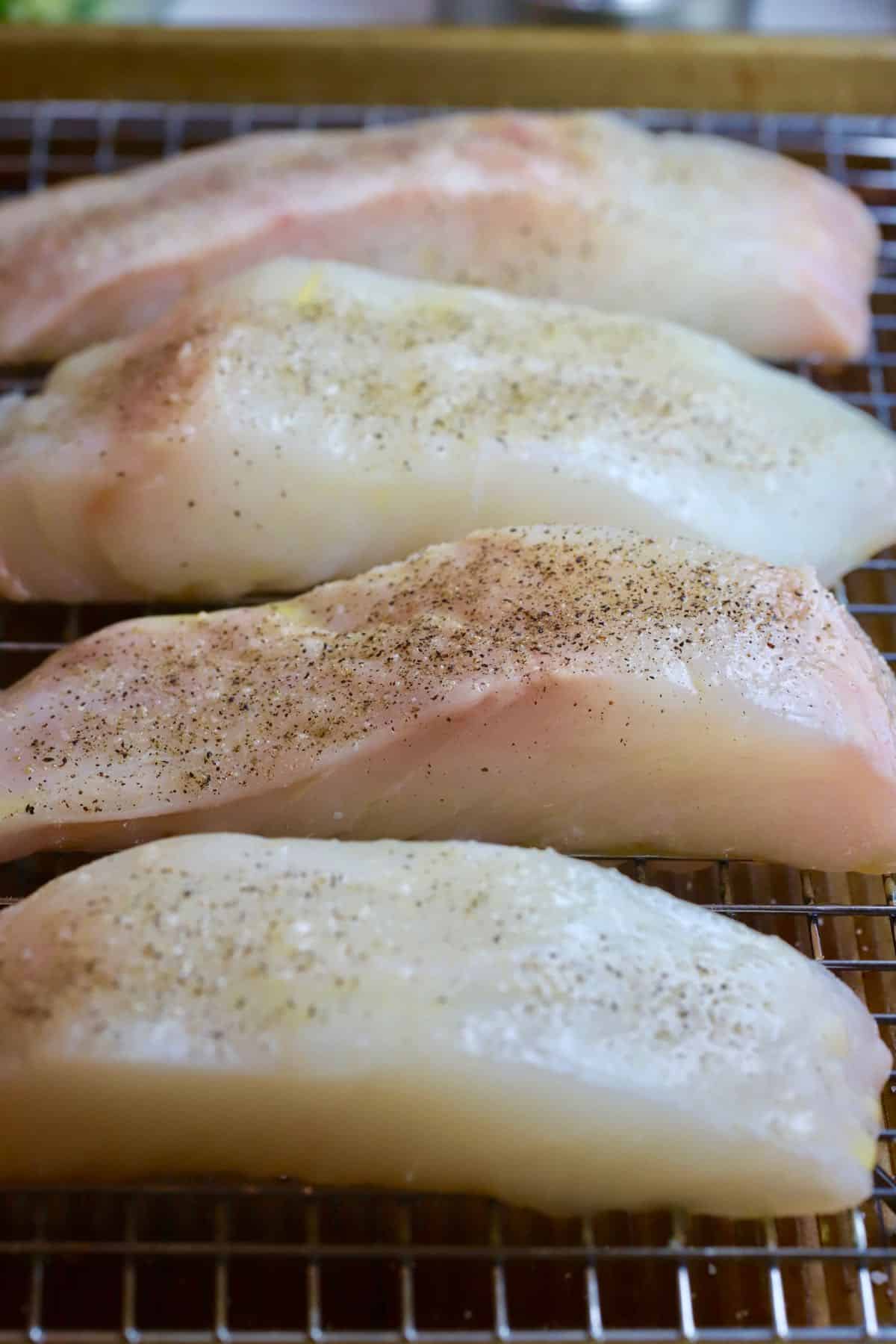 Four fish fillets on a wire baking rack. 