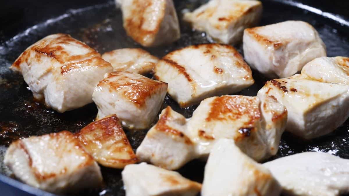 Cooking chicken pieces in a skillet.