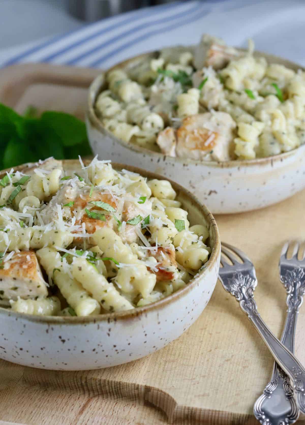 Two bowls full of chicken pesto pasta. 