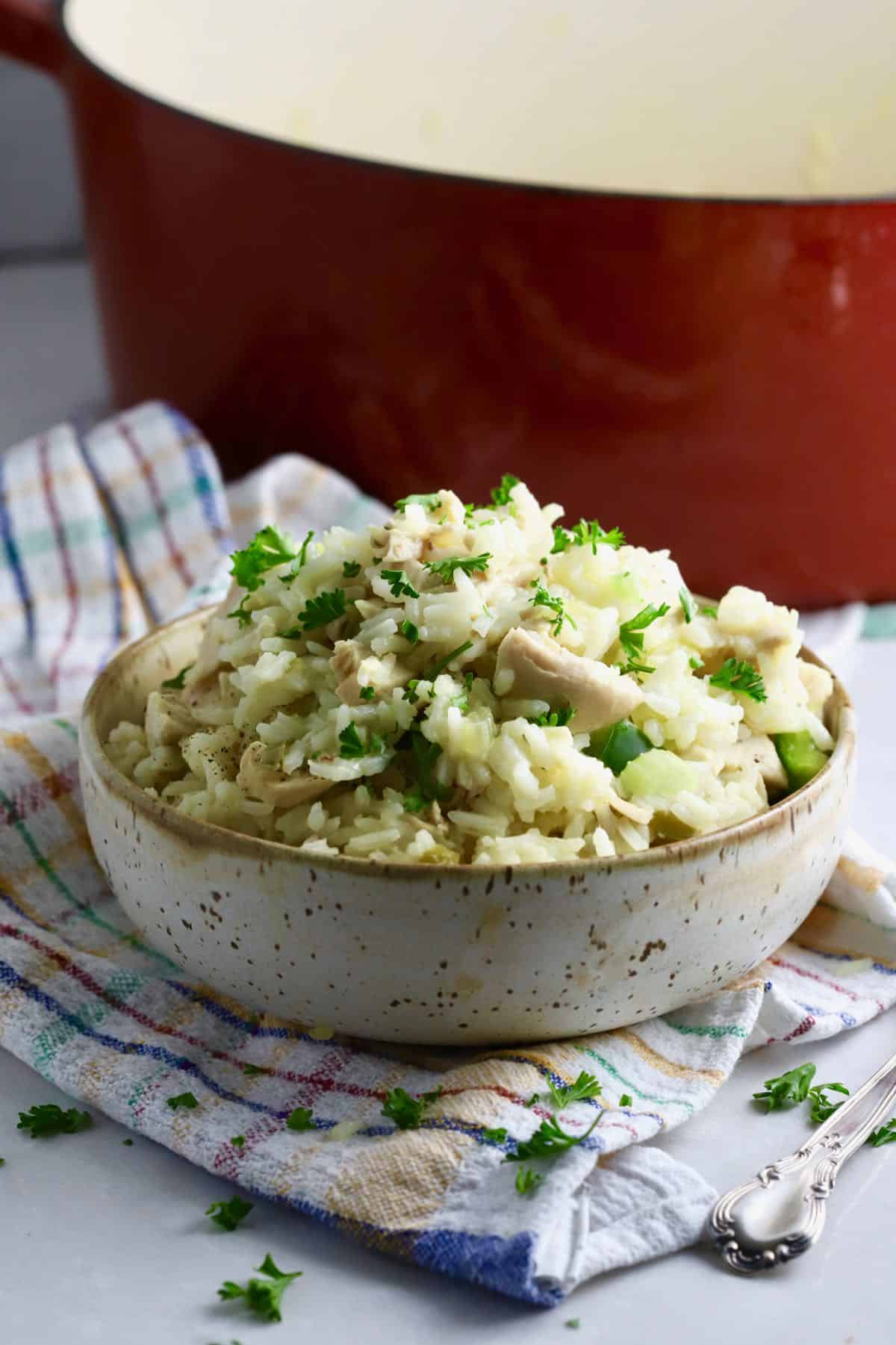 A pottery bowl full of chicken and rice. 