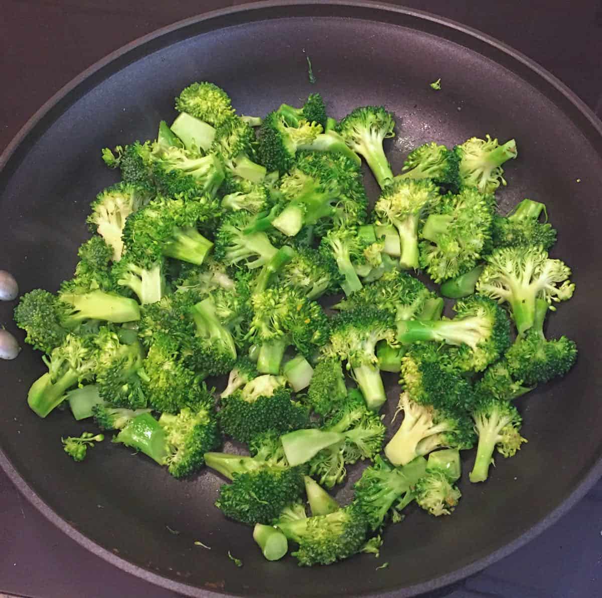 Broccoli cooking in a black skillet. 