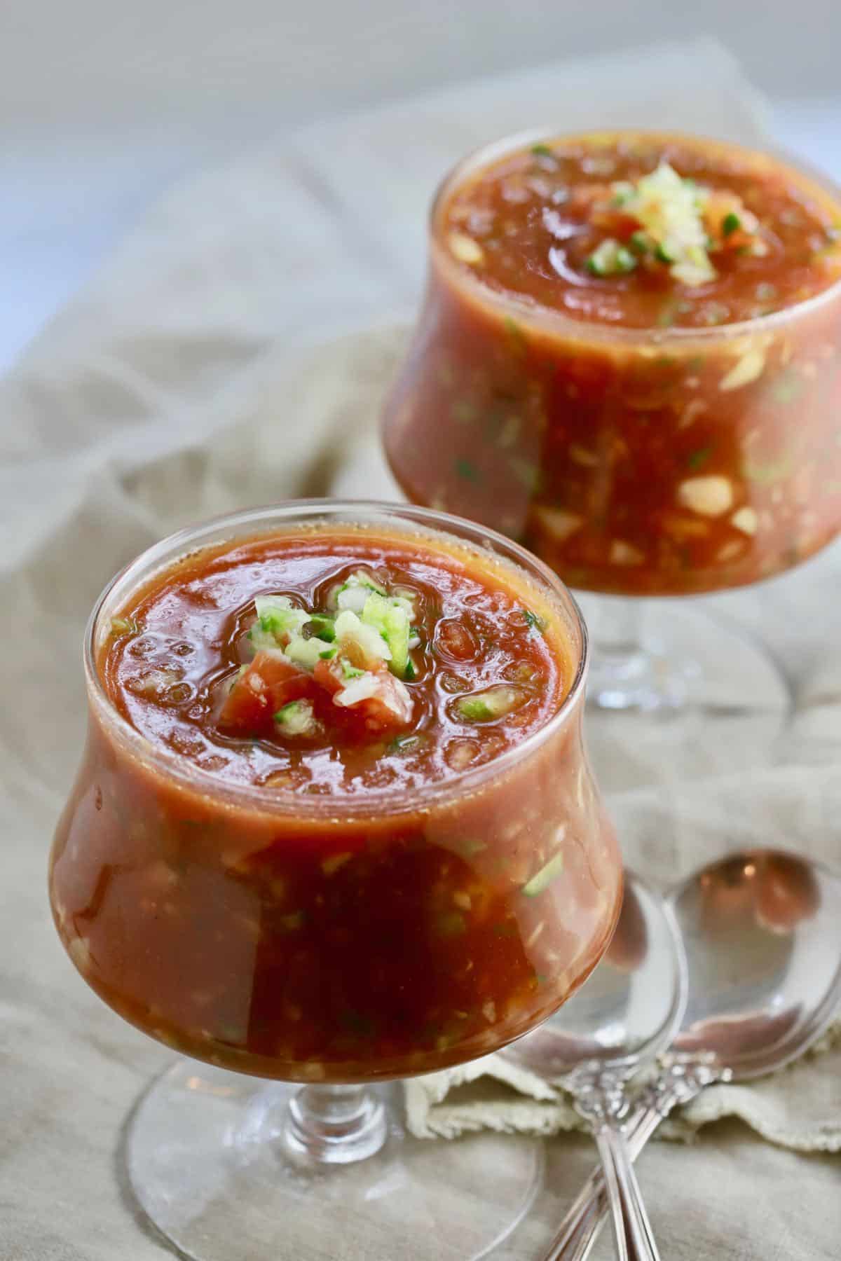 Two glass bowls full of cold Spanish soup. 