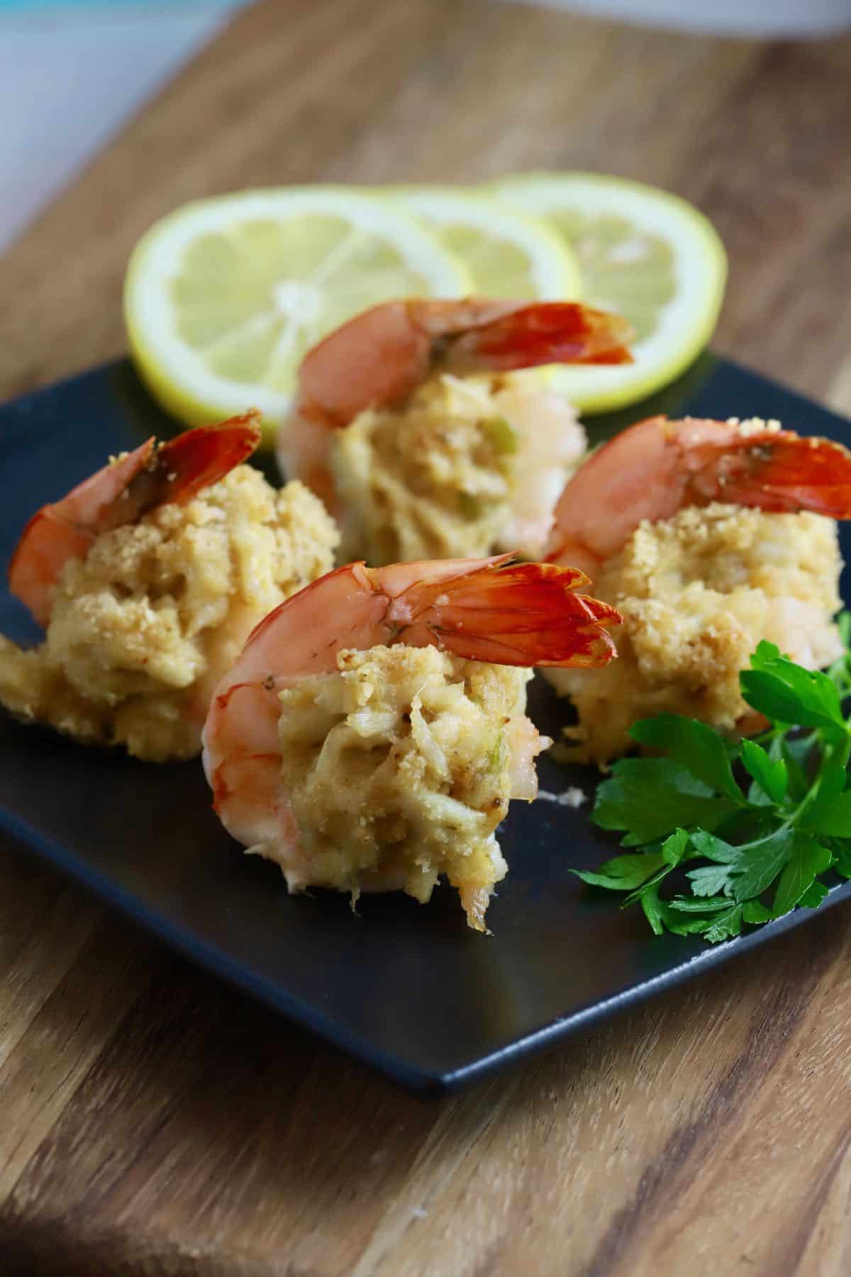 A black plate with four stuffed shrimp. 