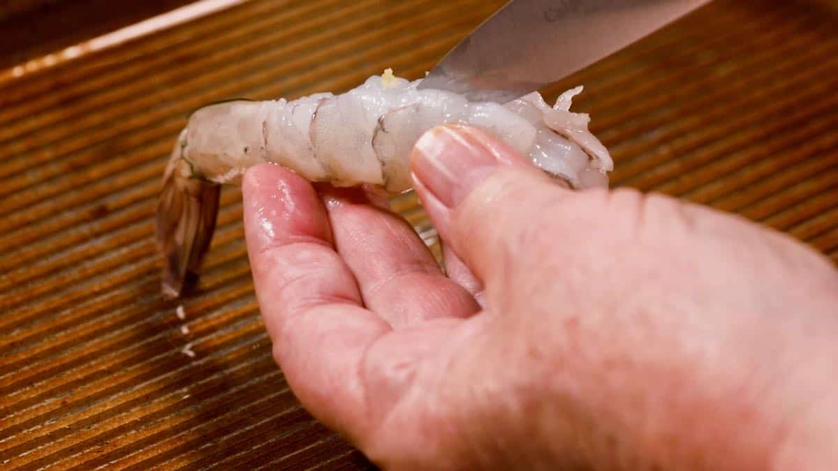 Using a knife to butterfly a shrimp. 