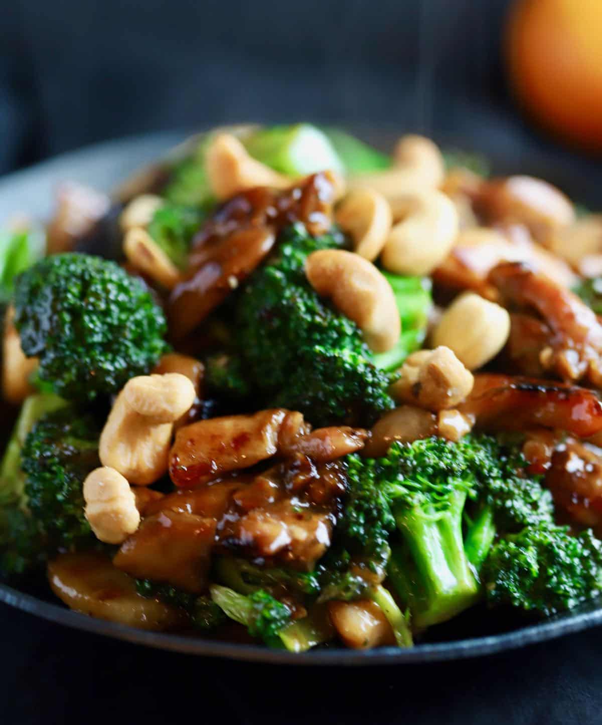 Pieces of chicken and broccoli florets in a black skillet. 