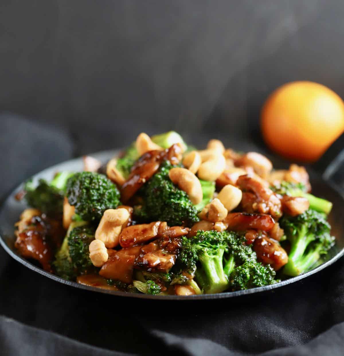 Chicken broccoli stir-fry topped with cashews in a black pan. 