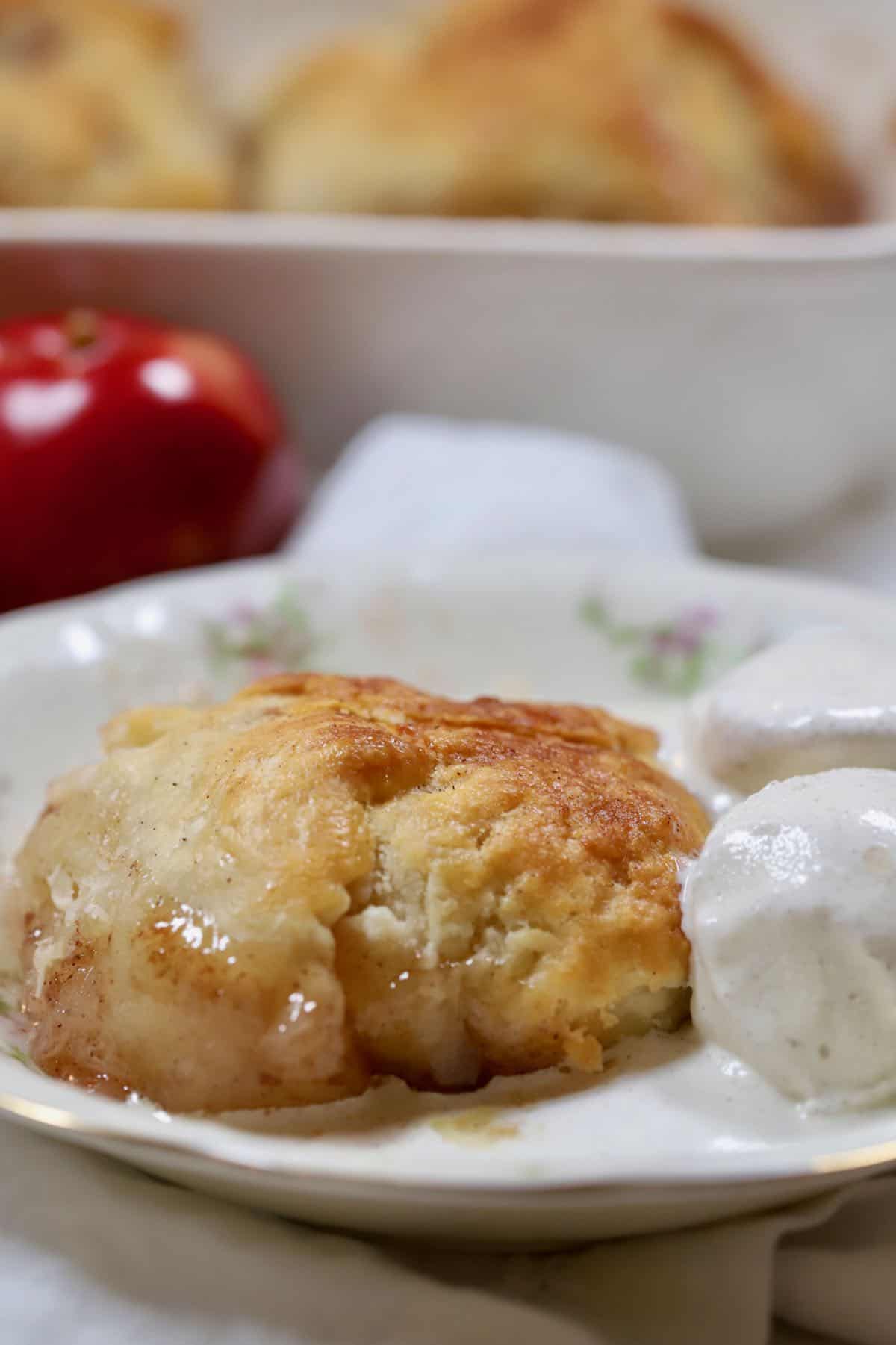 A china bowl with an apple dumpling a two scoops of ice cream.