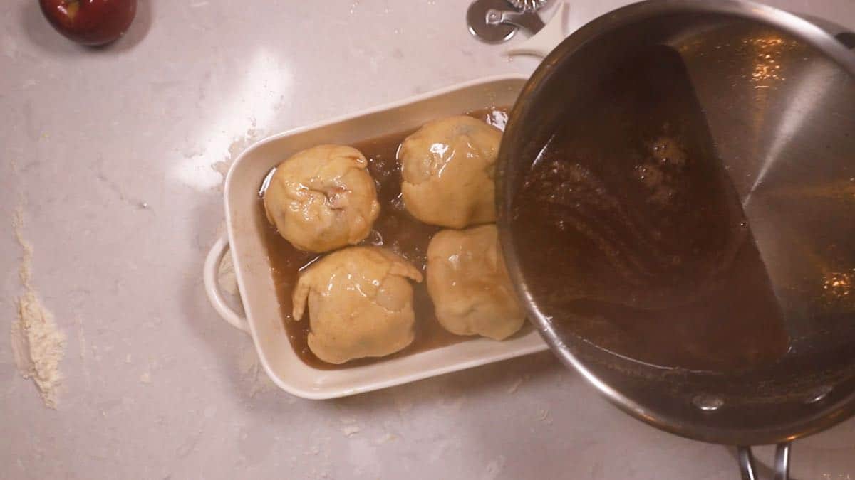 Pouring sauce over pastry covered apples. 