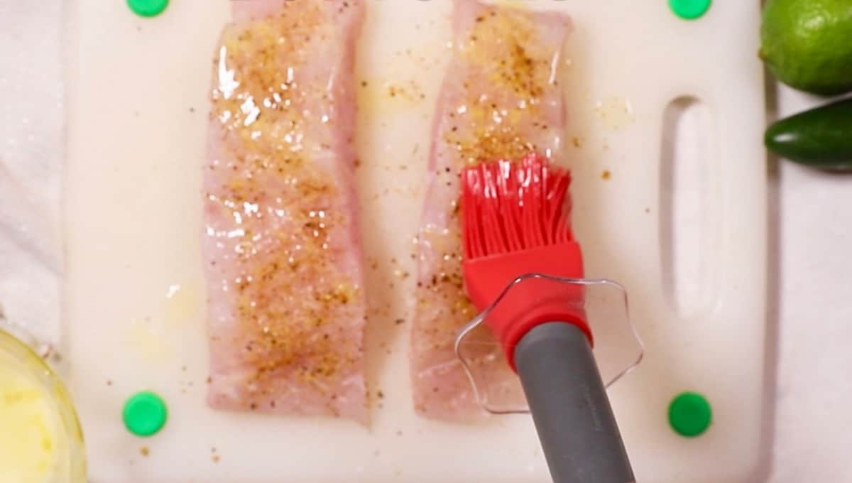 Brushing butter on a fish fillet. 