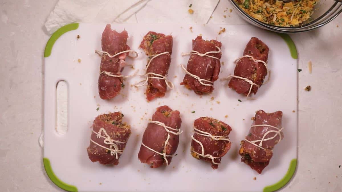 Stuffed pork braciole rolls tied with kitchen string. 