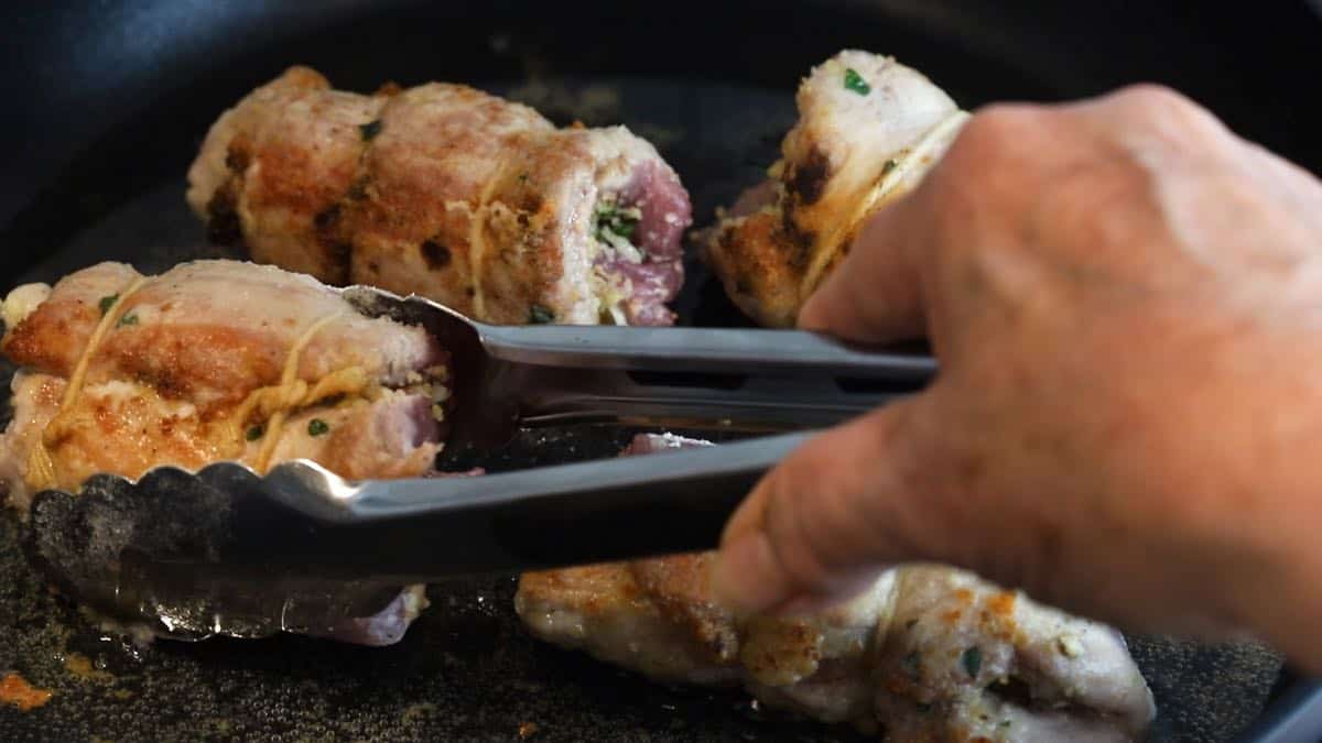 Searing braciole in a skillet. 