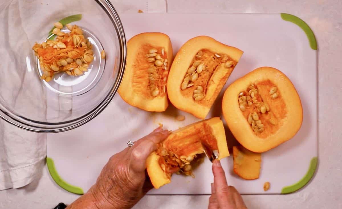 Using a spoon to scrape out pumpkin seeds from pumpkin pieces. 