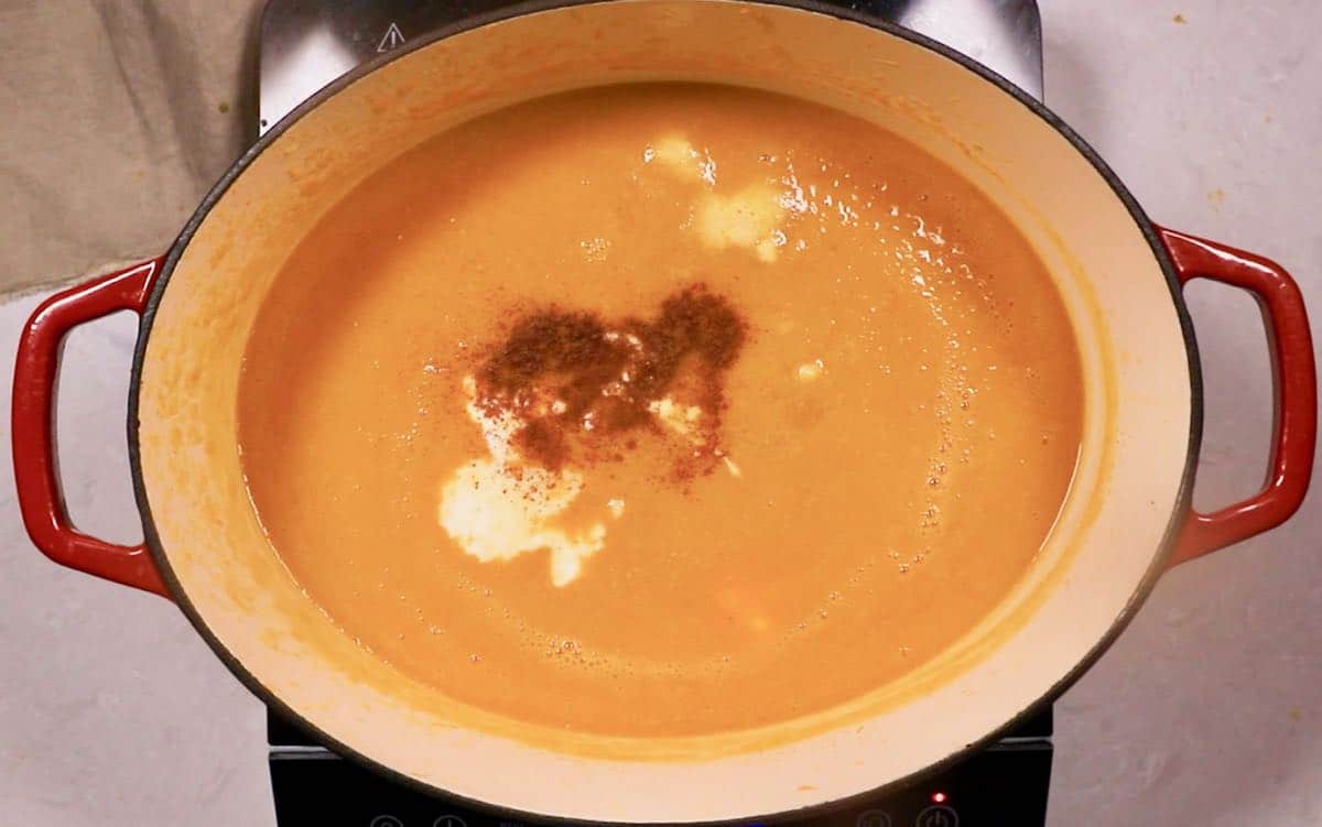 Pumpkin soup in a large Dutch oven cooking on the stove. 