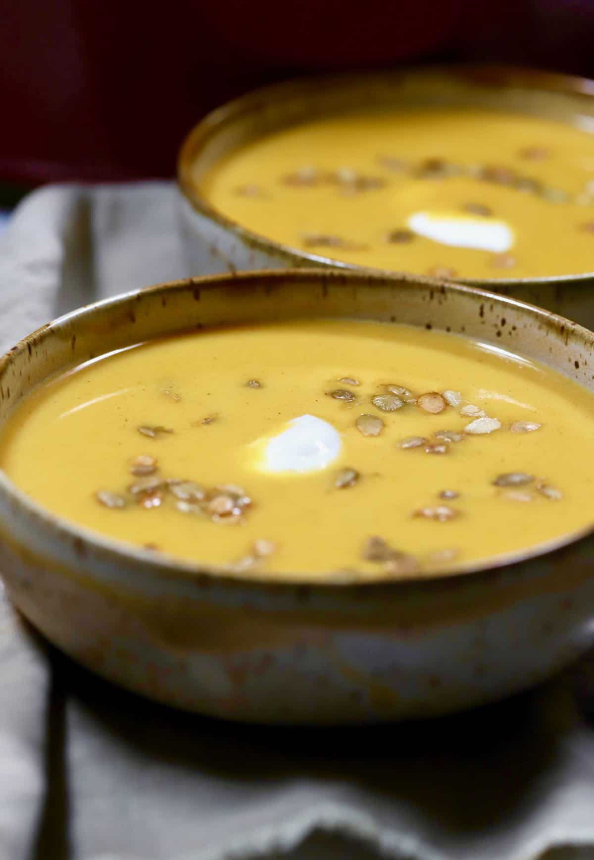 A brown pottery bowl full of pumpkin soup. 