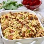 Cornbread dressing with sausage and pecans in a white serving dish.