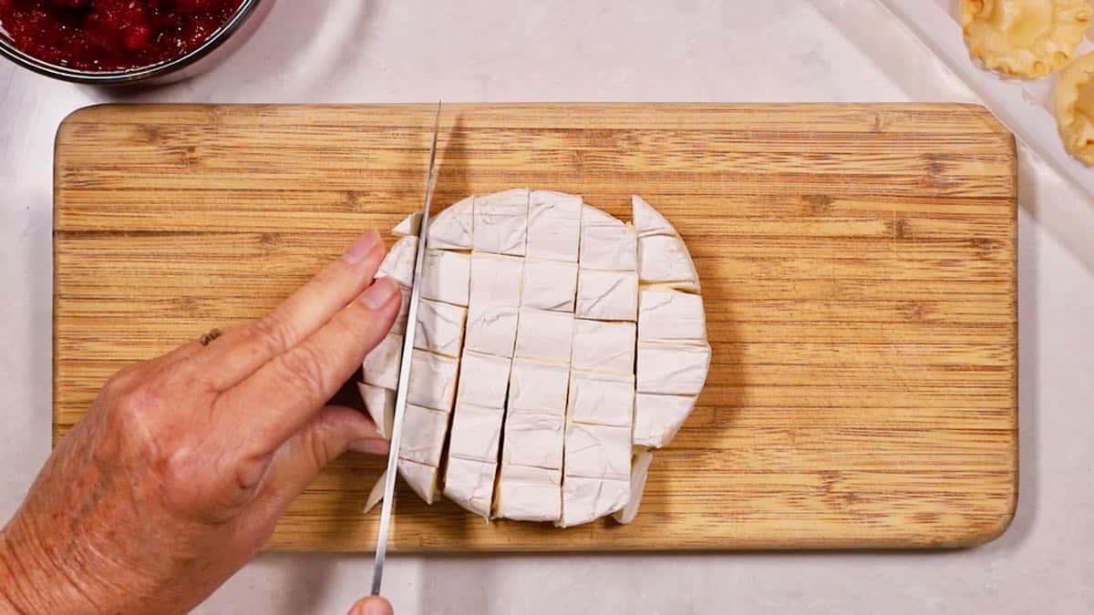 Brie cheese cut into cubes on a cutting board. 