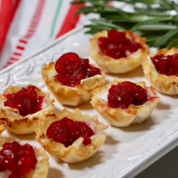 Cranberry brie bites on a white plate with festive napkin.