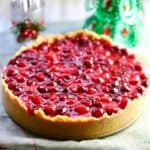 Cranberry cheesecake with a small Christmas tree behind it.