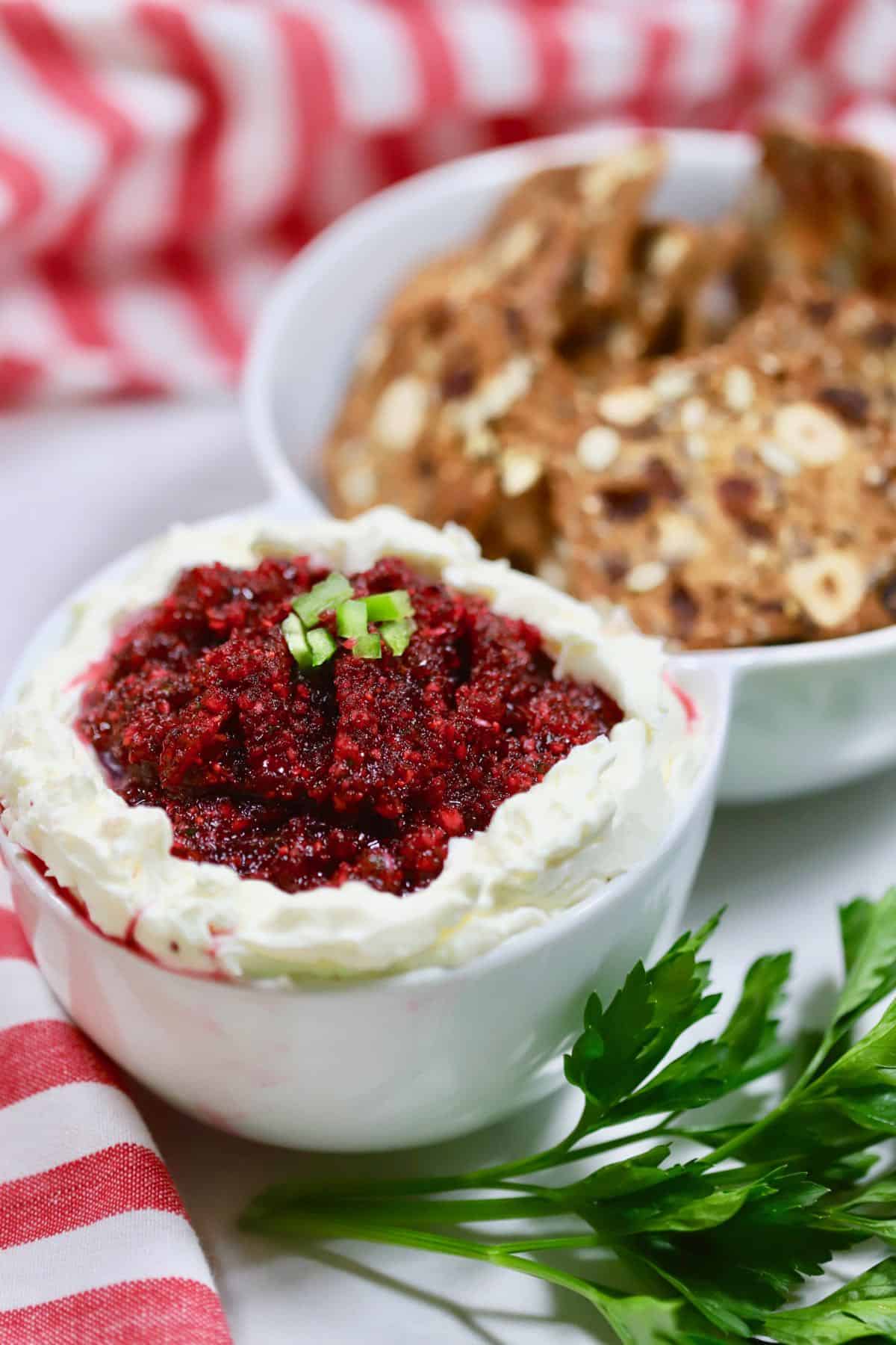Cranberry Jalapeno Cream Cheese Dip in a white serving dish with crackers. 
