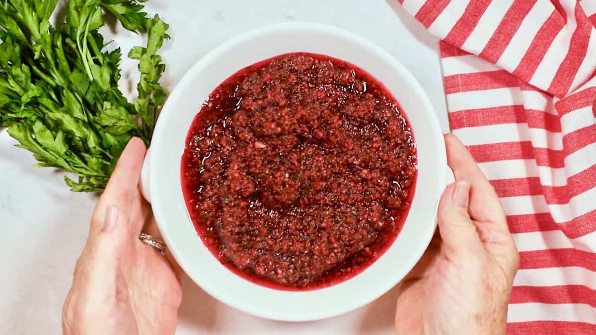 A white bowl with chopped up cranberries. 