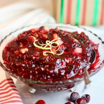 A glass dish full of cranberry sauce, topped with lemon peels.