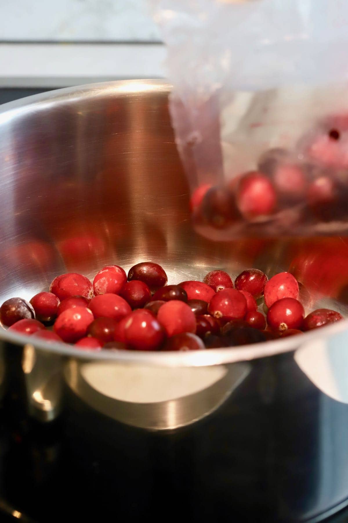 Pouring cranberries into a saucepan.