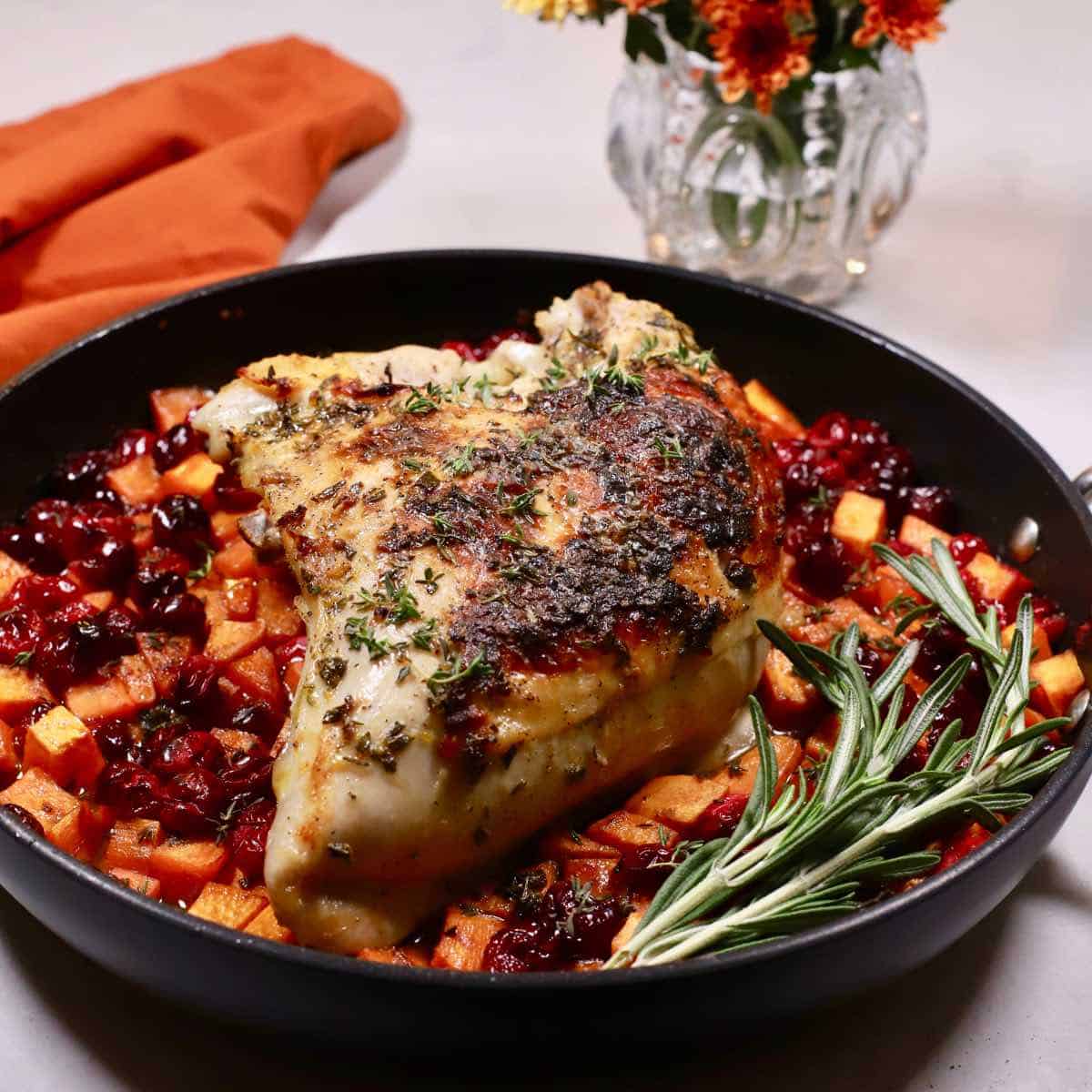 Roasted turkey breast with sweet potatoes and cranberries in a skillet.