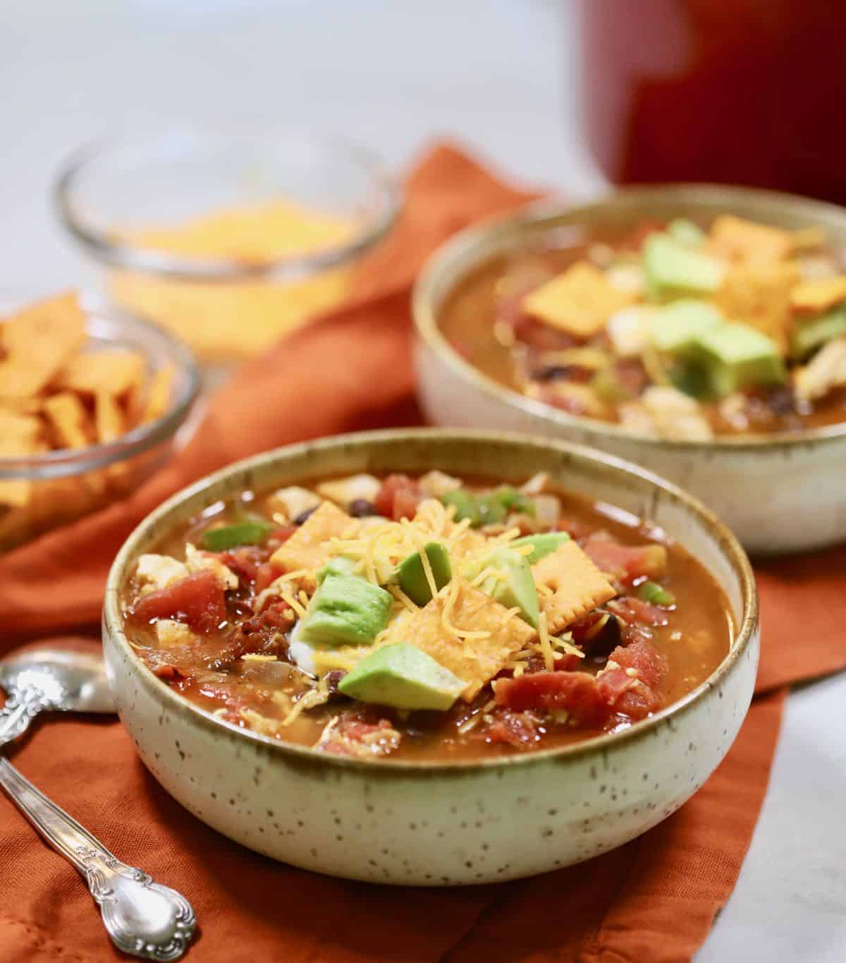 Two bowls of chili topped with sour cream and shredded cheese. 